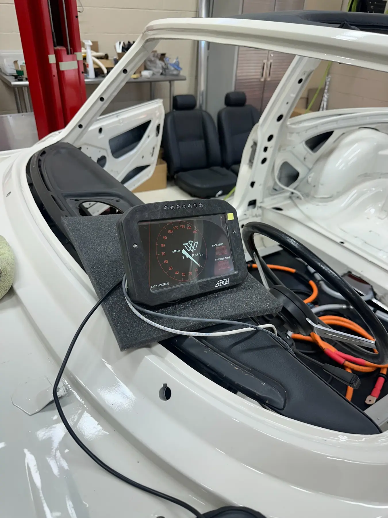 AEM digital dash powered during a temporary fit check in the open Triumph Stag cabin
