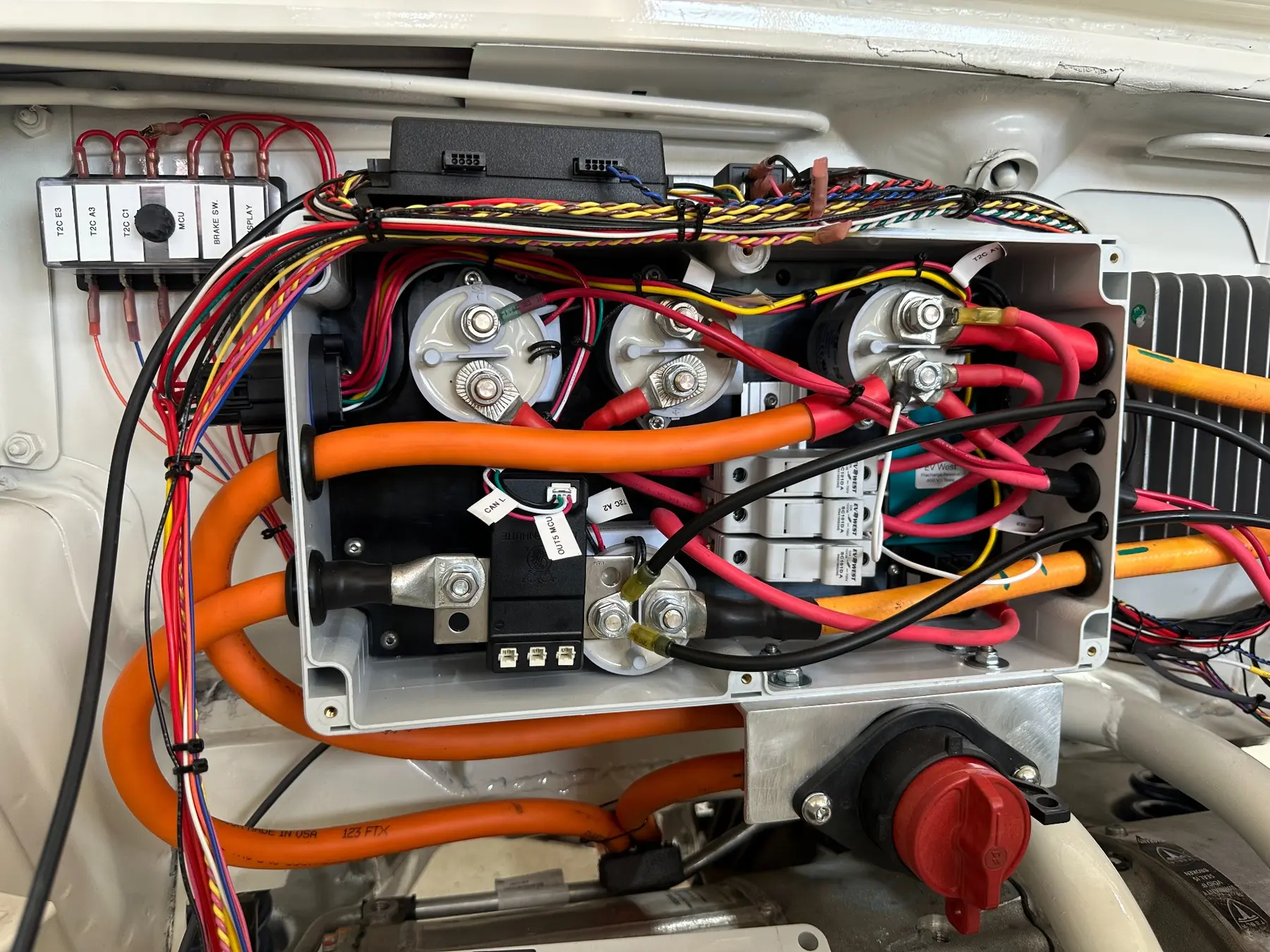 Open high-voltage distribution enclosure with contactors, fuses, control wiring, and orange cable